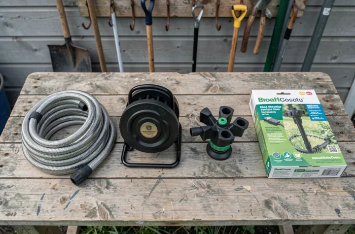 Comparatif de produits d'arrosage jardin posés sur un établi en bois extérieur