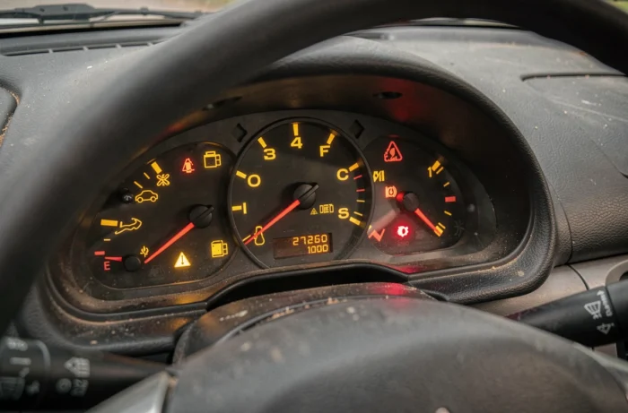 Tableau de bord d'une Peugeot 206 avec plusieurs voyants d'alerte allumés en orange et rouge